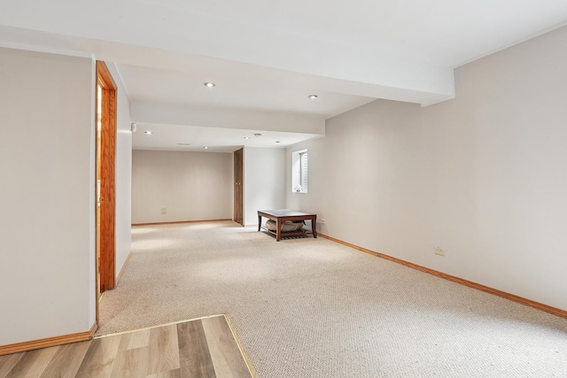 basement featuring baseboards, recessed lighting, light wood-style flooring, and light carpet