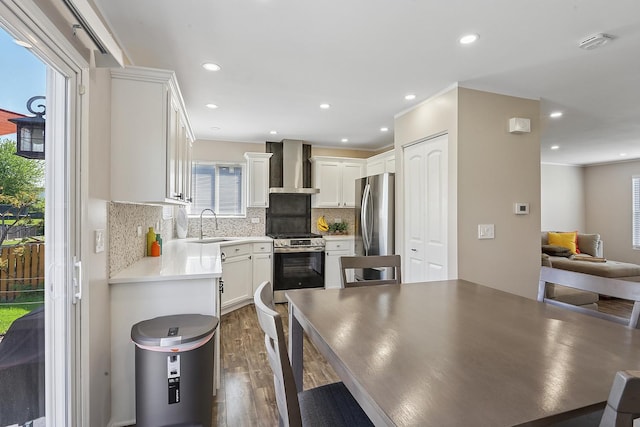 kitchen with wall chimney exhaust hood, stainless steel appliances, dark wood finished floors, backsplash, and a sink