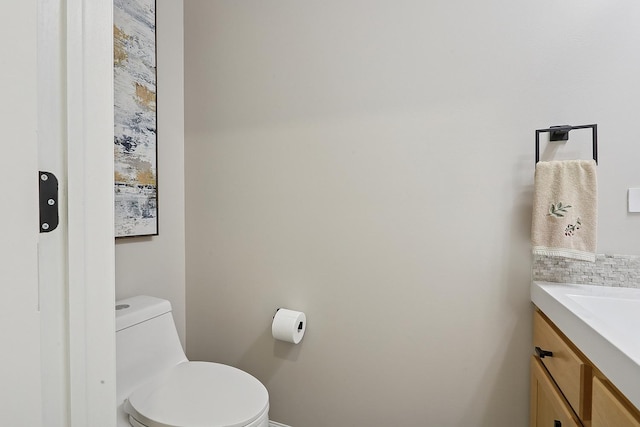 bathroom with toilet, vanity, and baseboards