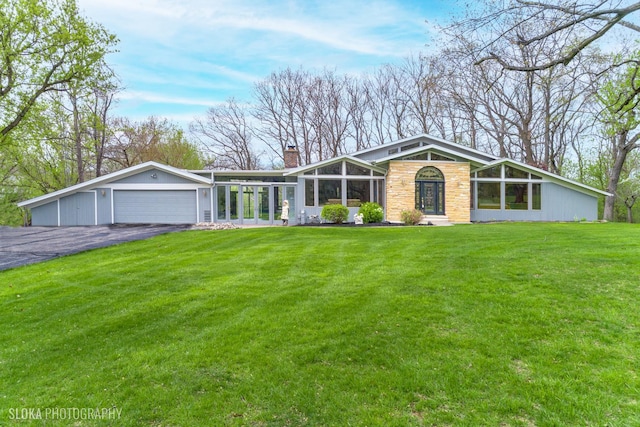 184A River Rd, Lake Barrington, IL 60010 - mid-century modern home featuring stone siding, a chimney, driveway, a front lawn, and an attached garage