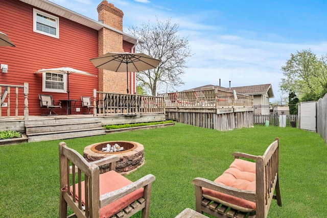 view of yard with fence, a wooden deck, and an outdoor fire pit