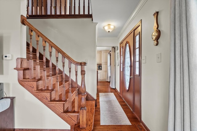 entryway with crown molding, dark wood-style flooring, and stairs