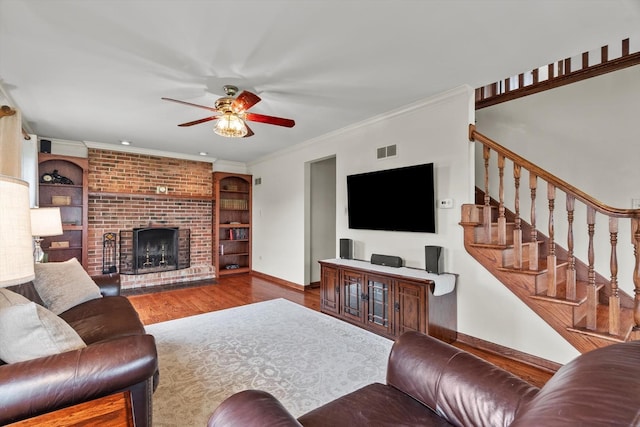 living room featuring visible vents, wood finished floors, baseboards, built in shelves, and a ceiling fan