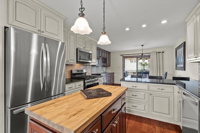 kitchen featuring appliances with stainless steel finishes, tasteful backsplash, a peninsula, wood counters, and recessed lighting