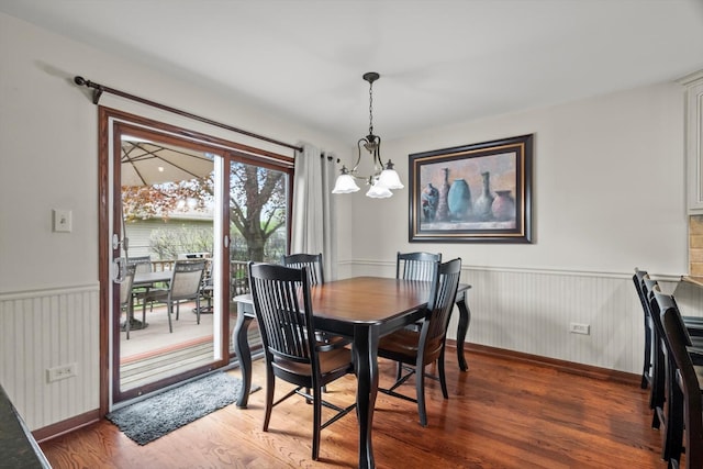 dining space featuring light wood-type flooring, wainscoting, baseboards, and a chandelier