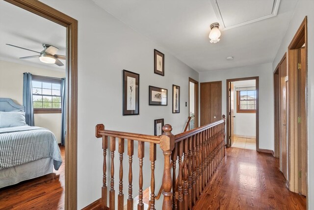 corridor featuring baseboards, wood finished floors, and an upstairs landing