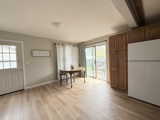 dining area with light wood-style floors, baseboards, and a textured ceiling
