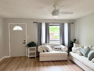 living area featuring baseboards, ceiling fan, and wood finished floors