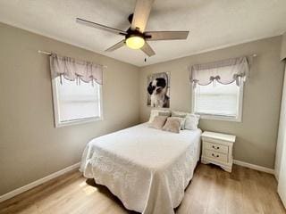 bedroom with a ceiling fan, baseboards, and light wood finished floors