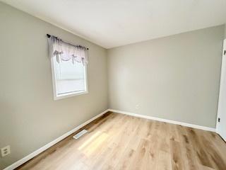 empty room featuring baseboards, visible vents, and wood finished floors