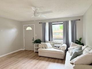 living area featuring baseboards, a ceiling fan, and wood finished floors