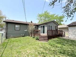 rear view of house with fence, a wooden deck, and a yard