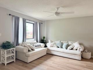 living area with a ceiling fan and wood finished floors