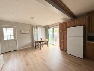 dining area with light wood-type flooring, baseboards, a wealth of natural light, and beamed ceiling