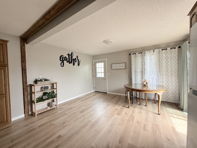 dining area featuring a textured ceiling, baseboards, and light wood finished floors