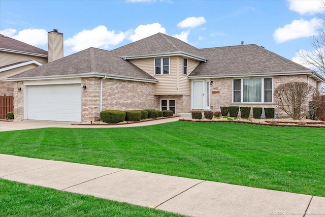 split level home featuring a garage, a front yard, and brick siding