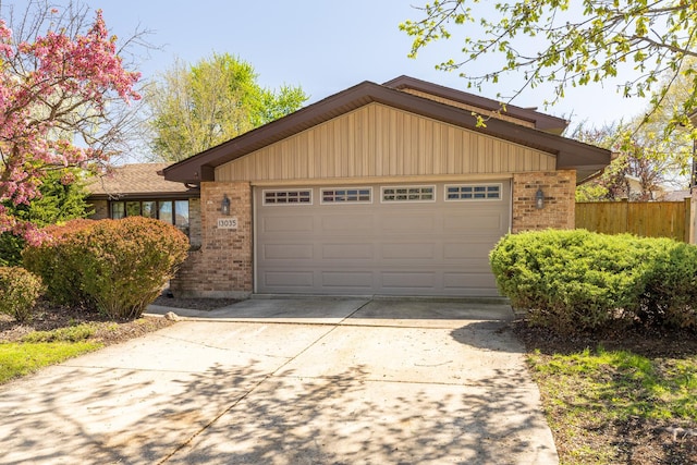 view of front of house featuring brick siding, driveway, and fence