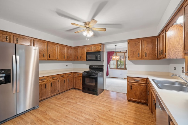 kitchen featuring brown cabinetry, a ceiling fan, a sink, black appliances, and light wood-style floors
