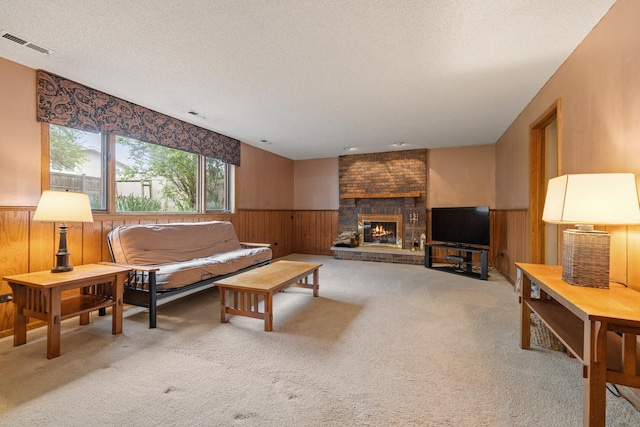 carpeted living area featuring wooden walls, a textured ceiling, visible vents, and wainscoting