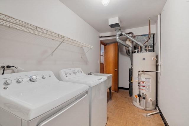 clothes washing area featuring separate washer and dryer, gas water heater, and laundry area