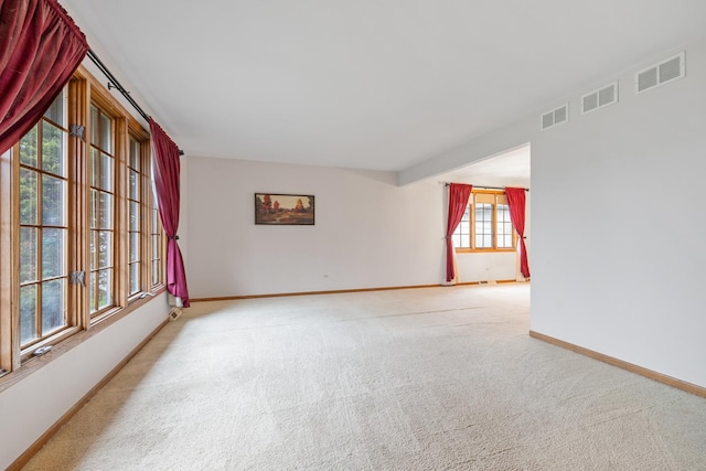carpeted spare room featuring baseboards and visible vents