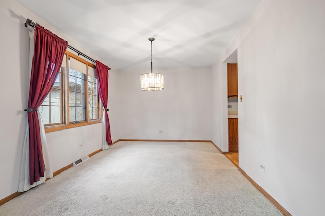 empty room featuring visible vents, carpet flooring, baseboards, and an inviting chandelier