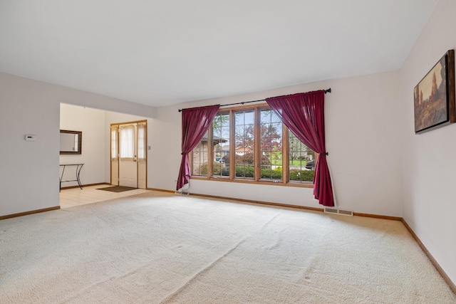 spare room featuring carpet flooring, baseboards, and visible vents