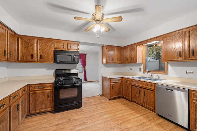 kitchen with brown cabinetry, ceiling fan, light countertops, a sink, and black appliances
