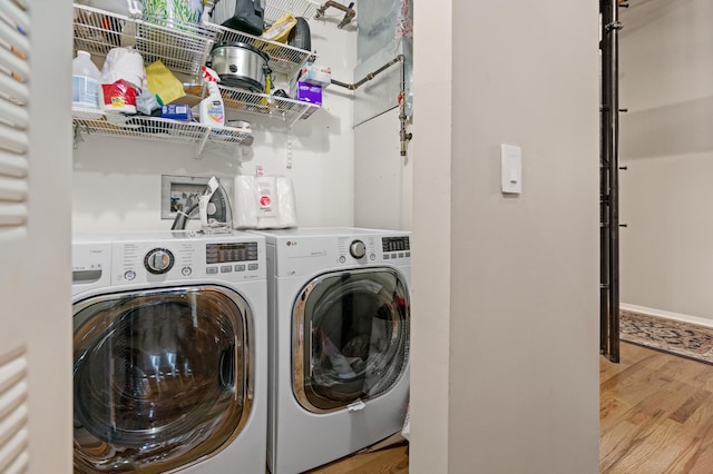 clothes washing area featuring laundry area, independent washer and dryer, and wood finished floors