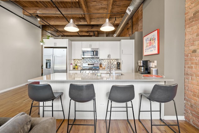 kitchen featuring baseboards, wood ceiling, a sink, light wood-style flooring, and stainless steel appliances
