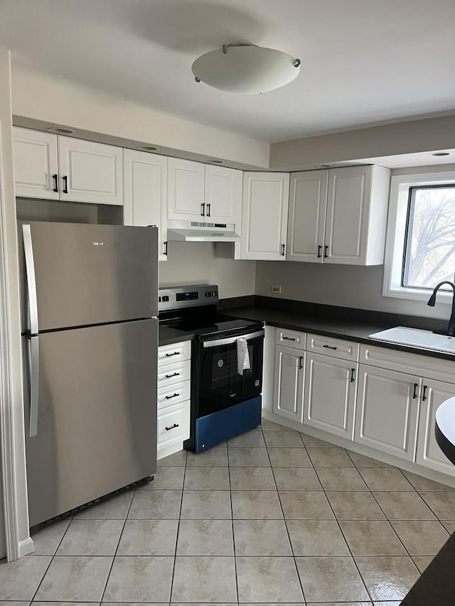 kitchen with a sink, freestanding refrigerator, electric stove, under cabinet range hood, and light tile patterned flooring