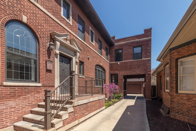 6907 S Constance Ave, Chicago, IL 60649 - view of exterior entry featuring brick siding, an attached garage, and concrete driveway