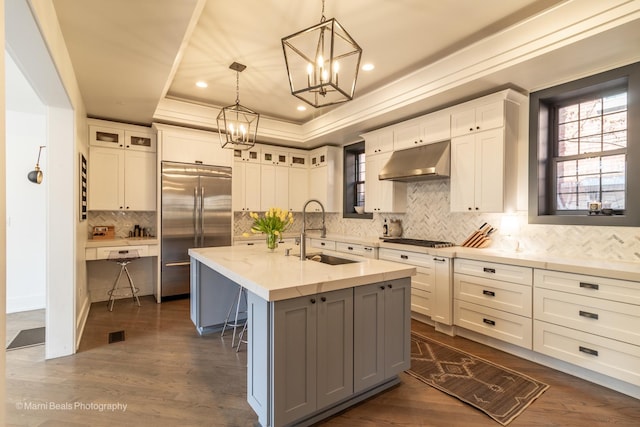 6907 S Constance Ave, Chicago, IL 60649 - kitchen featuring a tray ceiling, stainless steel built in fridge, a sink, an inviting chandelier, and under cabinet range hood