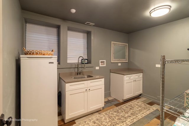 6907 S Constance Ave, Chicago, IL 60649 - laundry area featuring visible vents, light wood-style floors, baseboards, a sink, and cabinet space