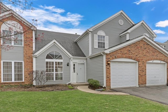 view of front of home with a shingled roof, a front lawn, brick siding, a garage, and aphalt driveway