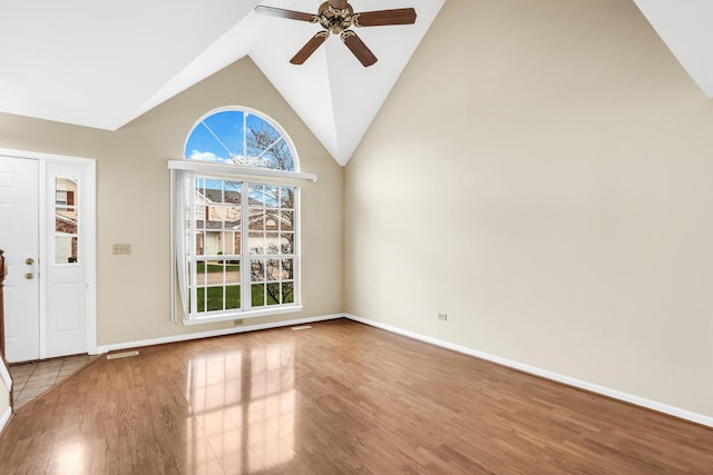 unfurnished living room featuring baseboards, ceiling fan, wood finished floors, and high vaulted ceiling