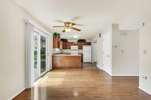 kitchen featuring a peninsula, ceiling fan, light wood-style floors, and white appliances