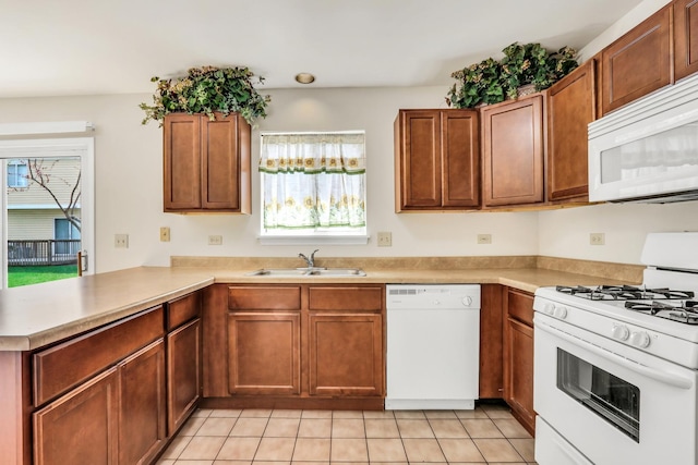 kitchen featuring a sink, a peninsula, a healthy amount of sunlight, and white appliances