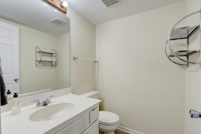 half bathroom featuring vanity, toilet, and visible vents