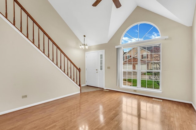 foyer featuring stairway, high vaulted ceiling, a wealth of natural light, and ceiling fan with notable chandelier