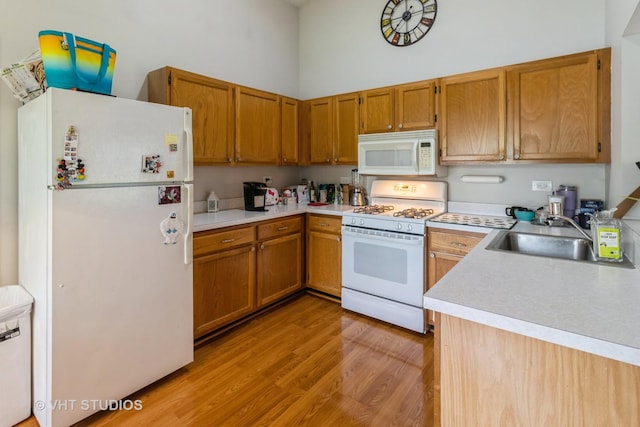 2048 Navarone Dr, Naperville, IL 60565 - kitchen featuring white appliances, a sink, a towering ceiling, light wood-style floors, and light countertops