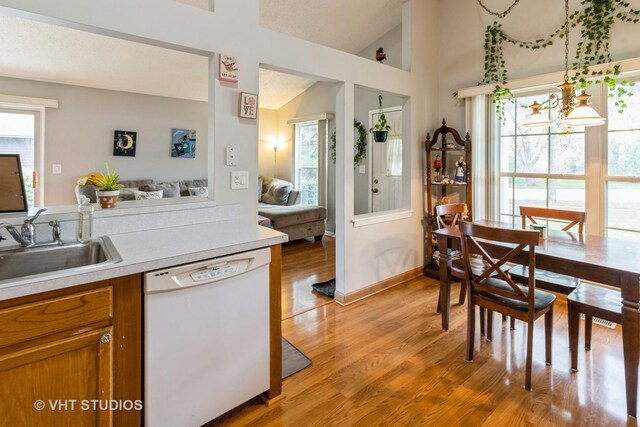 2048 Navarone Dr, Naperville, IL 60565 - kitchen with lofted ceiling, white dishwasher, a sink, brown cabinets, and light wood-style floors