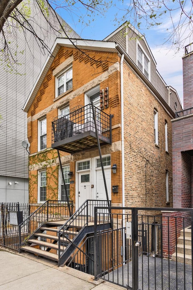 view of front of house featuring brick siding, a fenced front yard, and a balcony