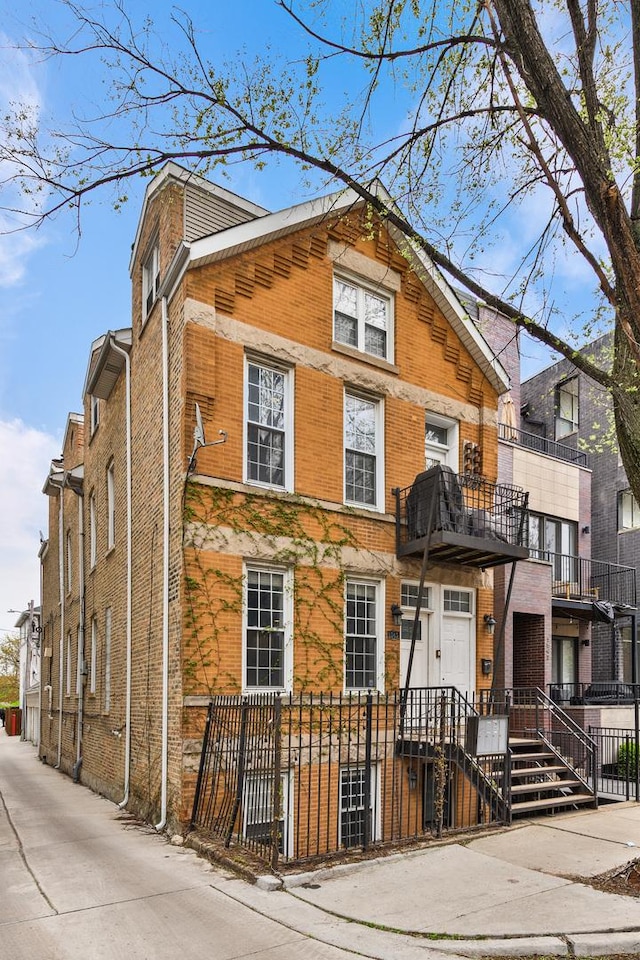 view of front of house with brick siding, a fenced front yard, and a balcony