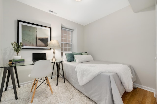 bedroom featuring baseboards, visible vents, and wood finished floors