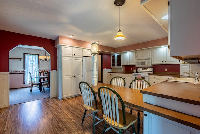 11 N Beech St, Princeton, IL 61356 - dining space featuring wood finished floors, a wainscoted wall, wallpapered walls, a chandelier, and arched walkways