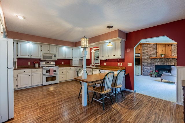 11 N Beech St, Princeton, IL 61356 - kitchen featuring white appliances, wood finished floors, a fireplace, dark countertops, and pendant lighting