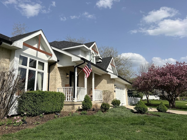 view of side of property with brick siding, an attached garage, a yard, and a porch