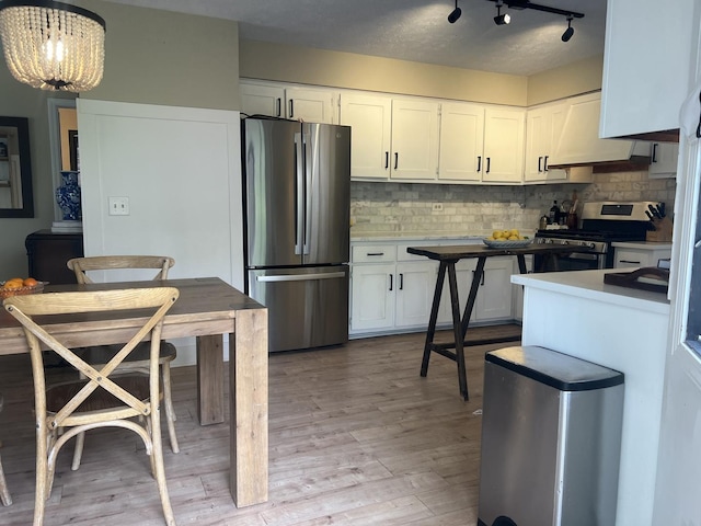 kitchen with light wood-style floors, white cabinetry, backsplash, and stainless steel appliances