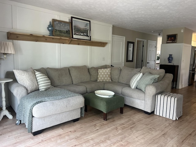 living room with a textured ceiling and light wood-type flooring